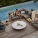 Boxhill's Arch Outdoor Corner Sofa w/ Teak Coffee Table 2 lifestyle image beside the pool with man and woman sitting down