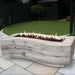 A light gray wood grain outdoor fire pit with sleek design placed on a tiled surface on an outdoor patio garden
