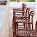 Five brown aluminum outdoor bar chairs arranged in a row in front of a concrete bar counter
