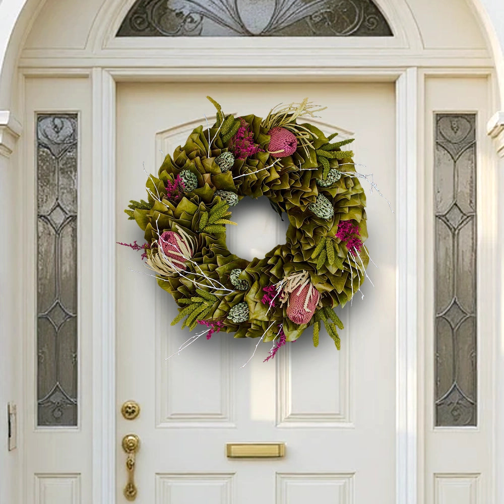Festive spring wreath with dried flowers and colorful red-pink and green accents on a white door