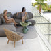 Boxhill's Glaze Outdoor Round Coffee Table lifestyle image on balcony with 2 women sitting down on a module sofa and Hive Outdoor Lounge Chair at the side