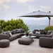 Boxhill's Capture Outdoor Pouf lifestyle image with Capture Module Sofa and Capture Coffee Table beside the pool with large umbrella shade