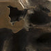 Close-up of a sculptural abstract object with organic, cave-like hollows and metallic brushed surfaces in dark bronze, brown, and charcoal tones.