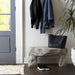 Cast Stone Outdoor Bench holding a black tote beside an entryway door, with shoes underneath.