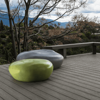 Grey and green concrete pebble garden seat on a wooden deck with scenic view of trees and distant hills