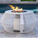 A white outdoor metal powdered coated fire pit table with lava rocks and flames on top placed beside the pool