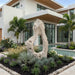 Colossal Cast Stone Single-Hole Sculpture surrounded by tropical planting beside a modern home’s pool.