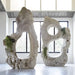 Colossal Cast Stone Single-Hole Sculpture beside a two-hole sculpture, both styled with trailing greenery indoors.