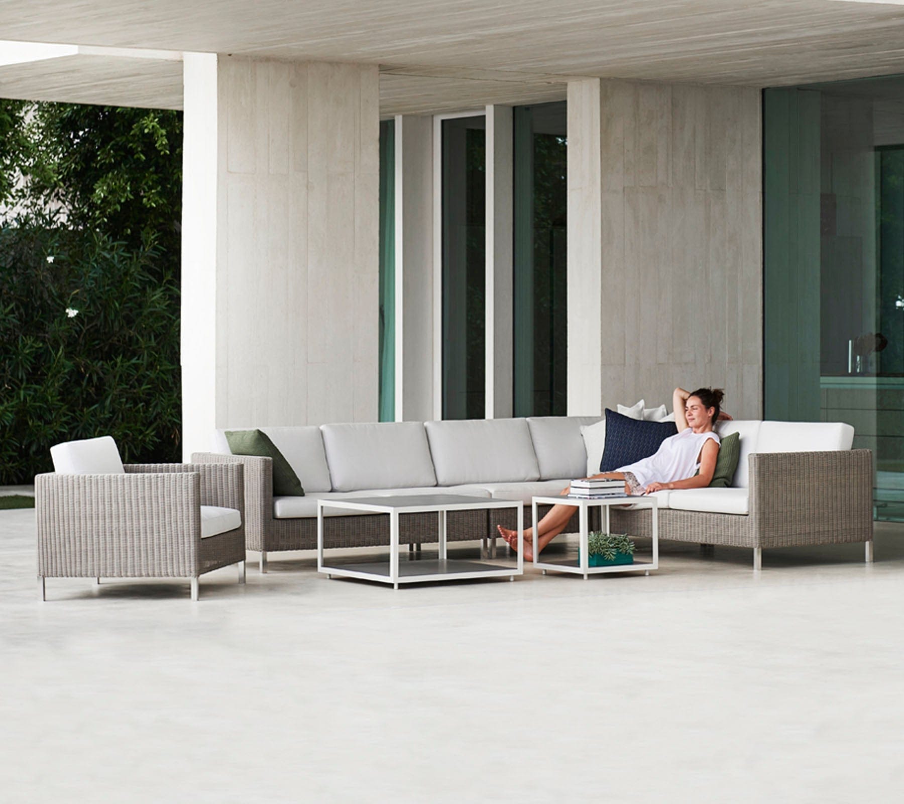 Boxhill's Connect Lounge Chair lifestyle image at patio with other module sofa and a woman sitting down 
