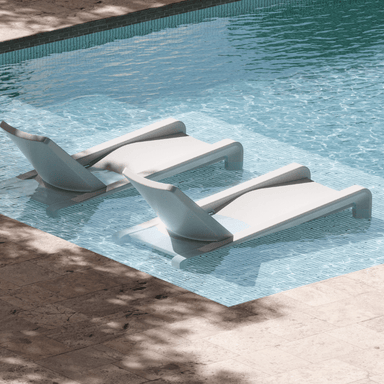 2 modern white in pool chaise loungers partially submerged in the shallow end of a pool