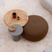 Patio coffee table with round wooden top, gray round side table, and brown fabric footstool on a tiled patio floor