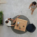 Aerial view of a modern outdoor setting with a square wooden outdoor cafe table, a man sitting in a chair, and a woman standing