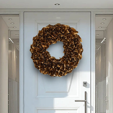 Glossy gold lacquer wreath displayed on a modern white front door with side glass windows.