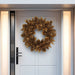 Decorative gold pinecone wreath with a radiant finish on a modern white front door.