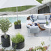 Boxhill's Grow Umbrella Base and Planter Box with Wheels lifestyle image at poolside with man and woman sitting down on a sofa