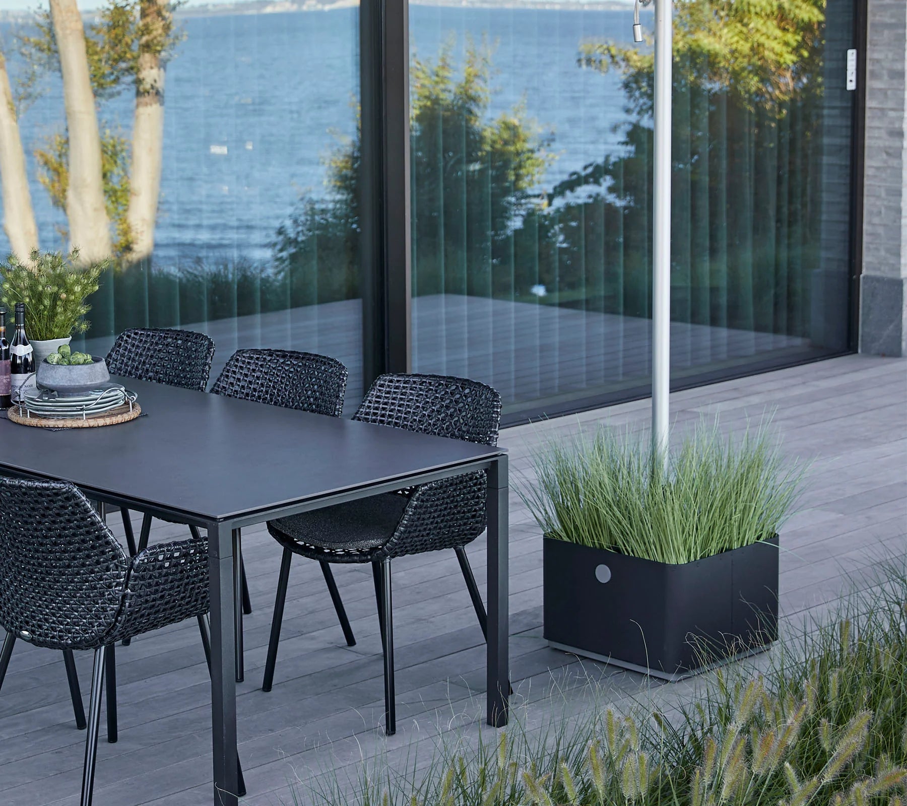 Boxhill's Grow Umbrella Base and Planter Box with Wheels lifestyle image beside dining table and dining chairs at patio
