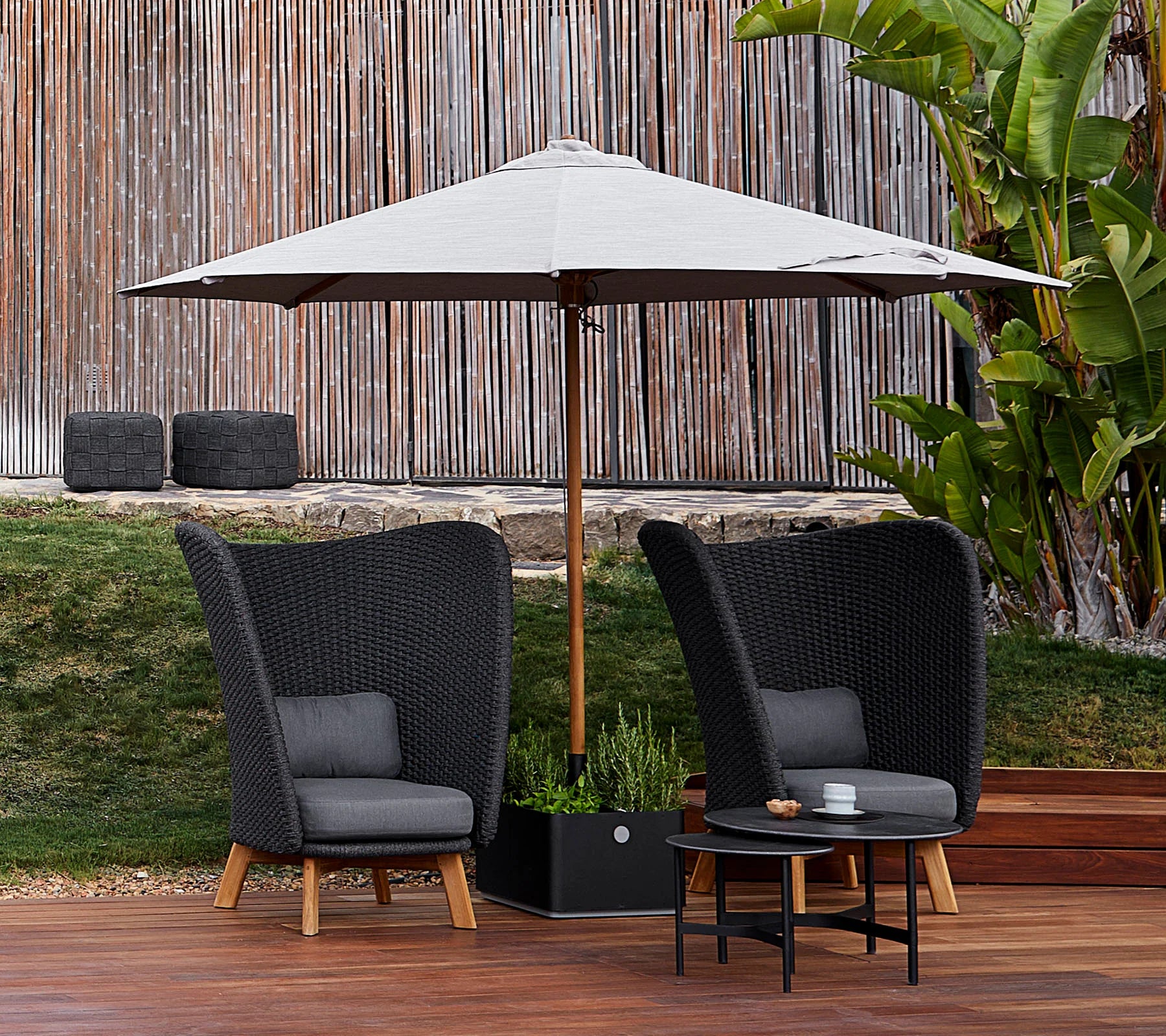 Boxhill's Grow Umbrella Base and Planter Box with Wheels lifestyle image in the middle of 2 lounge chairs mounted with parasol