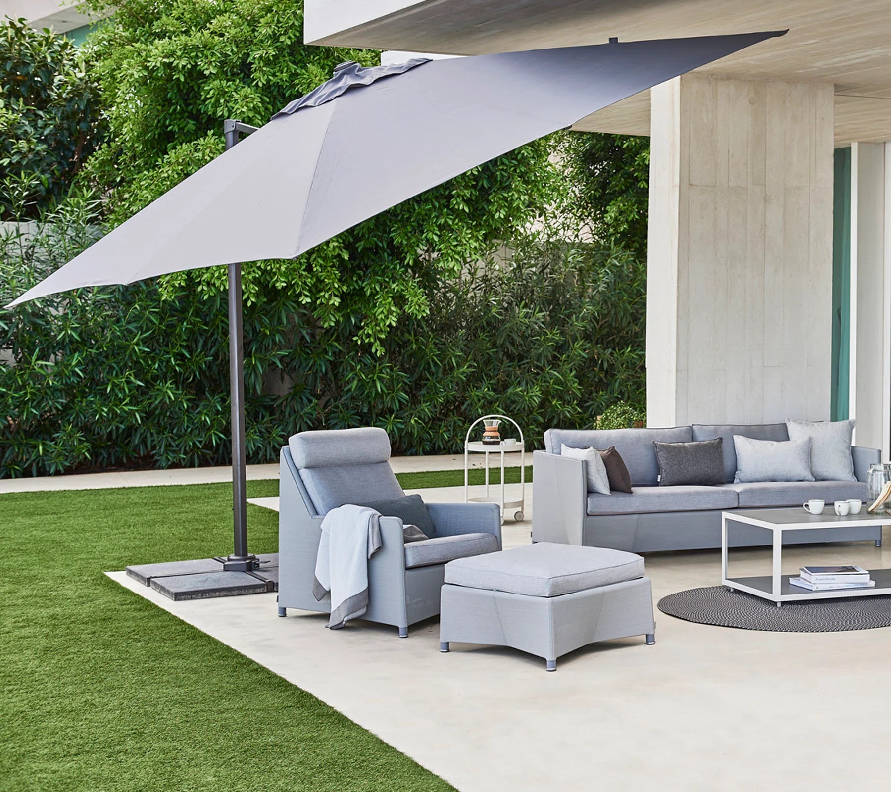 Boxhill's Hyde Luxe Tilt Aluminum Parasol | 3x3 m lifestyle image with 3-seater sofa, lounge chair and footstool at patio