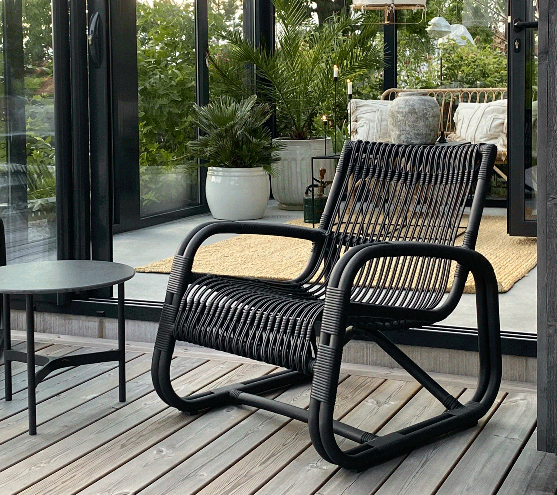 Boxhill's Curve Lounge Weave Outdoor Chair Graphite lifestyle image with round table at patio