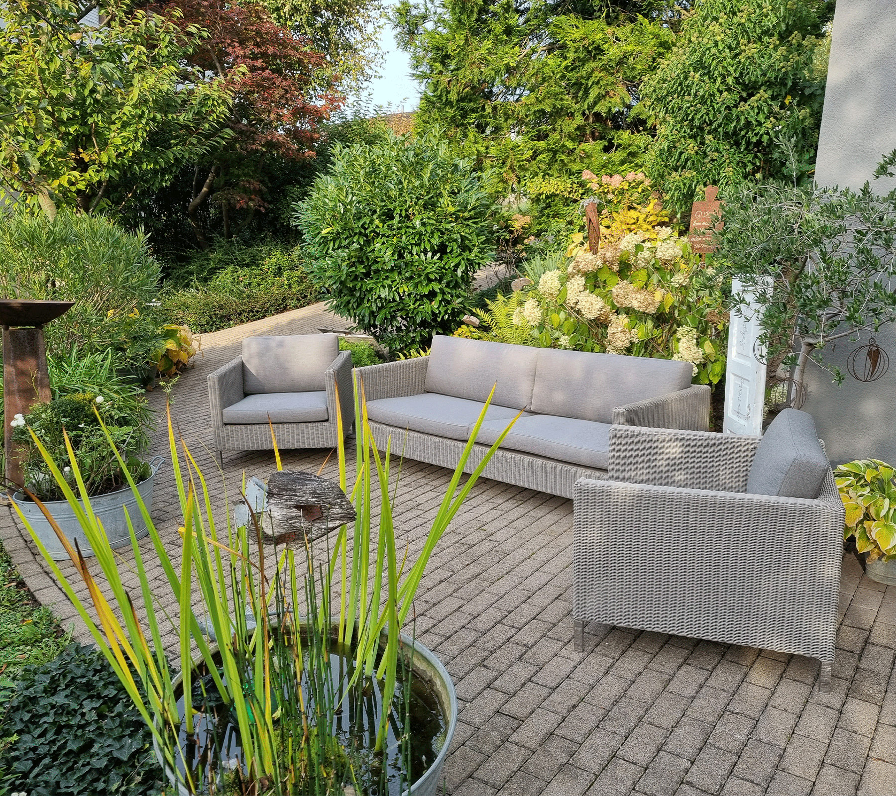 Boxhill's Connect 3-Seater Weave Sofa Natural lifestyle image with Connect Lounge Chair at the garden
