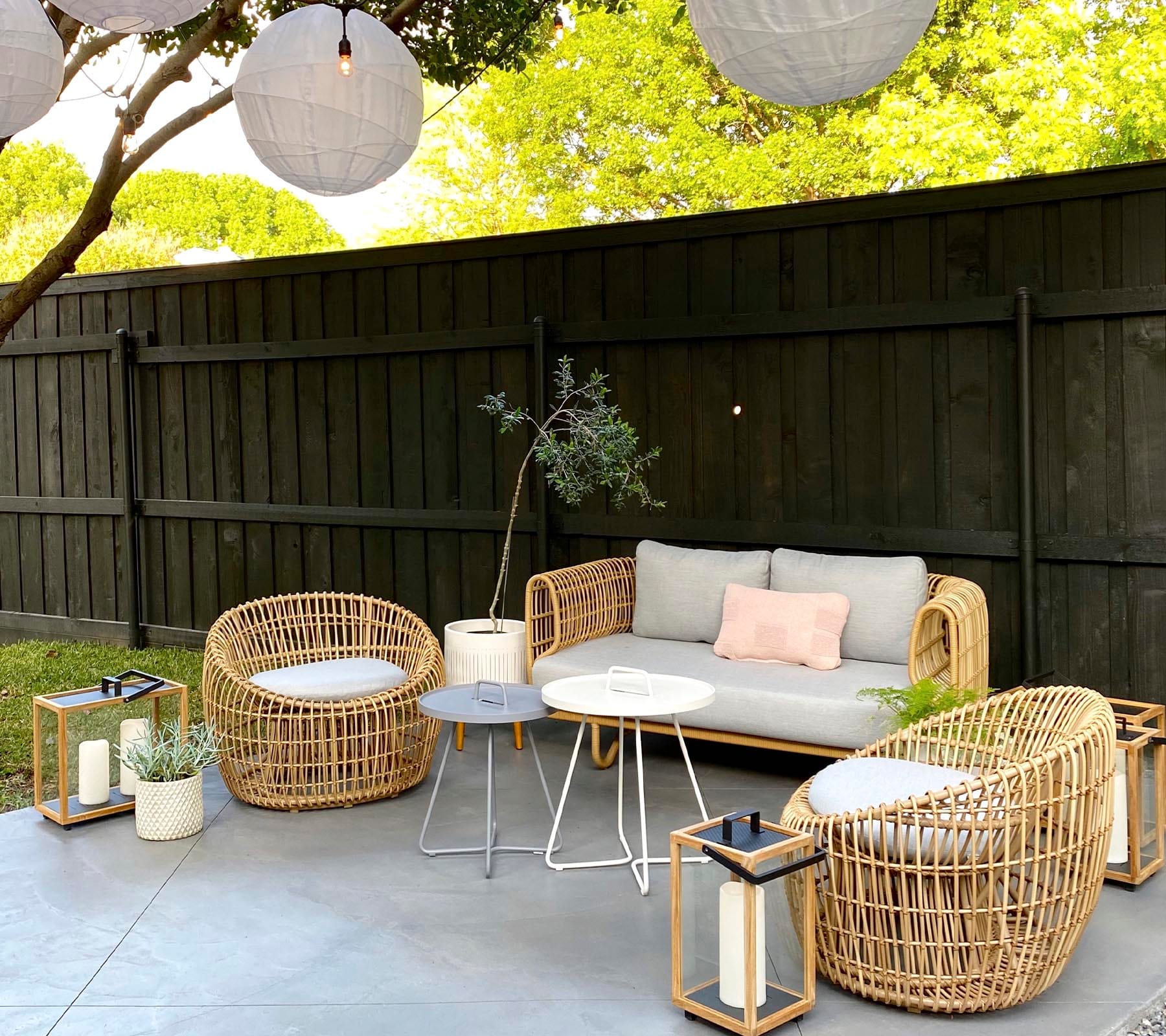 Boxhill's Nest 2-Seater Sofa lifestyle image at patio with Nest Round Rattan Chair, 2 small round table and Lighthouse Outdoor Large Teak Lantern 