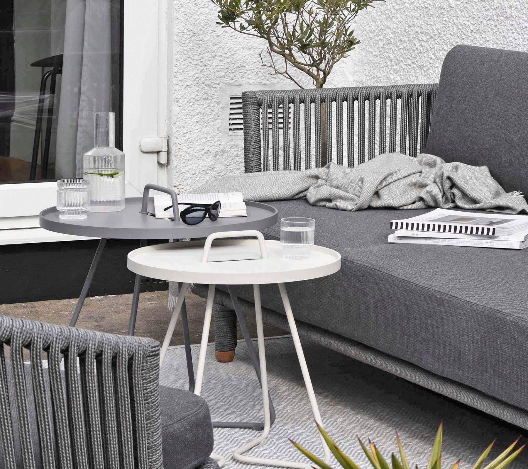 Boxhill's Moments 2-Seater Right Module Sofa lifestyle image at patio with a fabric cloth and books on top, and 2 round table in front 