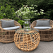 Boxhill's Nest Round Rattan Chair lifestyle image at patio with Nest Footstool/Coffee Table Outdoor with plant in a vase on top