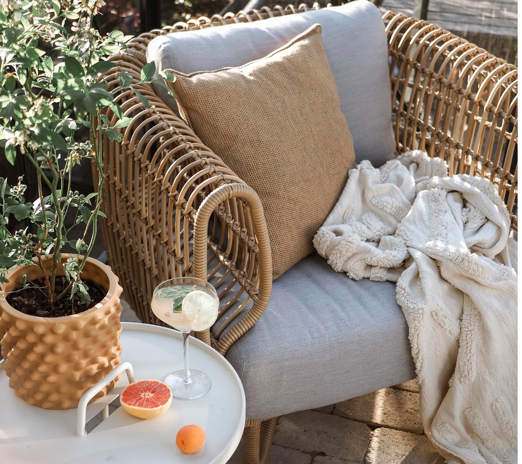 Boxhill's Nest Lounge Chair Lifestyle image at patio with pillow and a fabric cloth on top