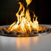 Close up view of a round outdoor metal powdered coated fire pit with vibrant flames burning over lava rocks