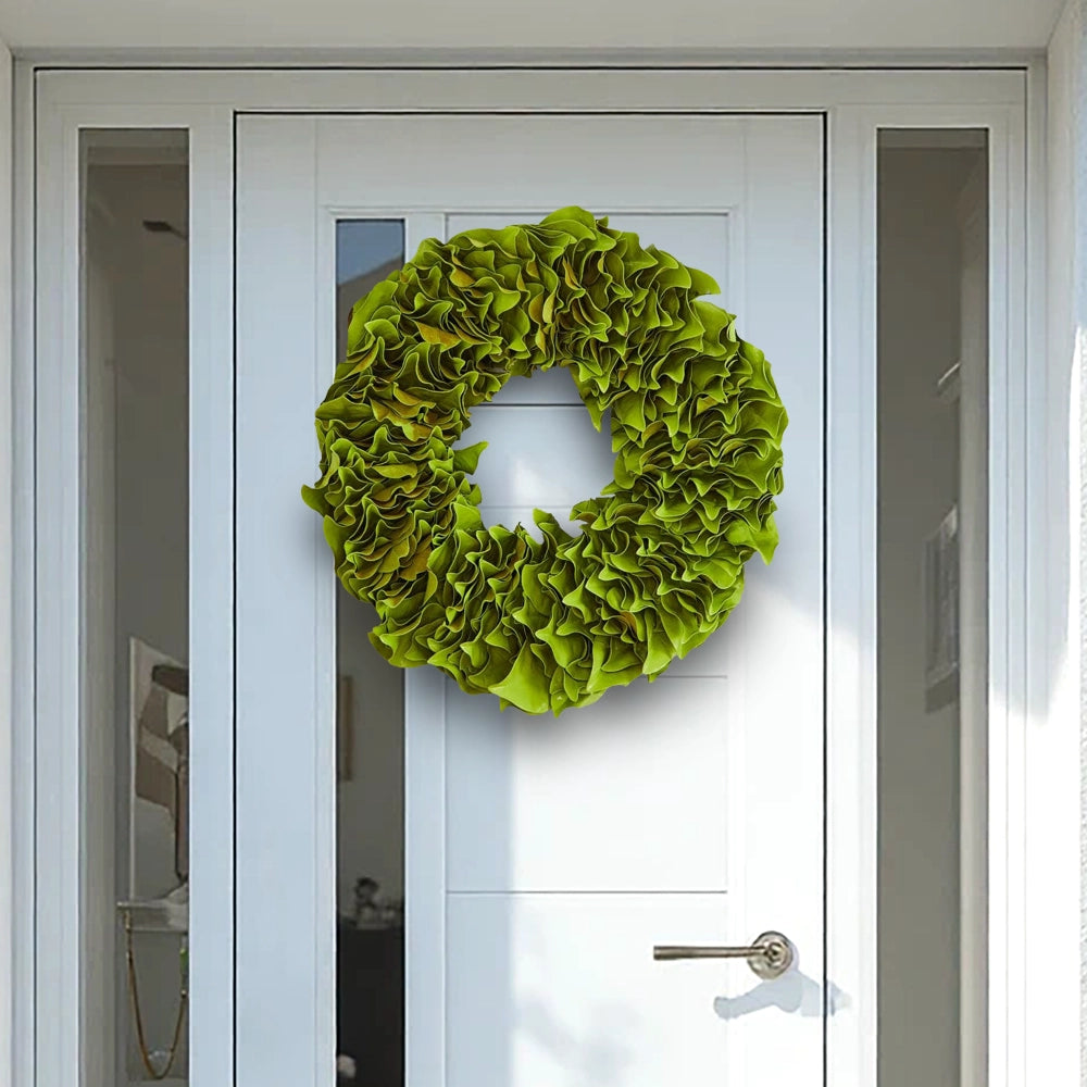 Bright green lacquer wreath with glossy finish on a modern white front door with glass panels.