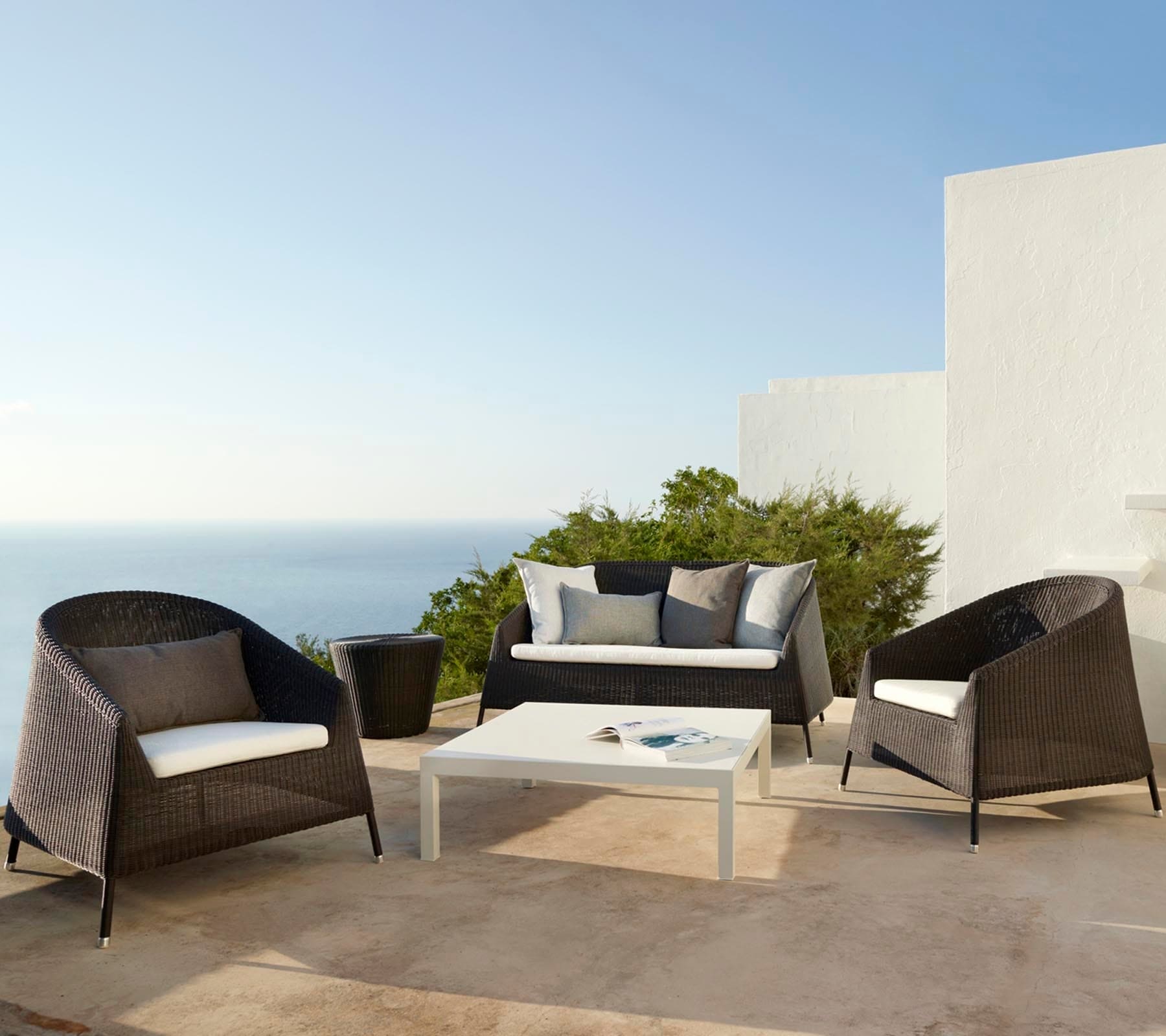 Boxhill's Kingston Outdoor Stackable Lounge Chair lifestyle image with Kingston Stackable Outdoor 2-Seater Sofa and a square white table at patio