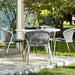 Boxhill's Lean Stackable Outdoor Garden Chair French Weave lifestyle image at patio with white round table and 2 glasses of water and a bottle container on top