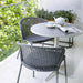 Boxhill's Lean Stackable Outdoor Garden Chair French Weave lifestyle image on balcony with a round table with pot and a cup on top