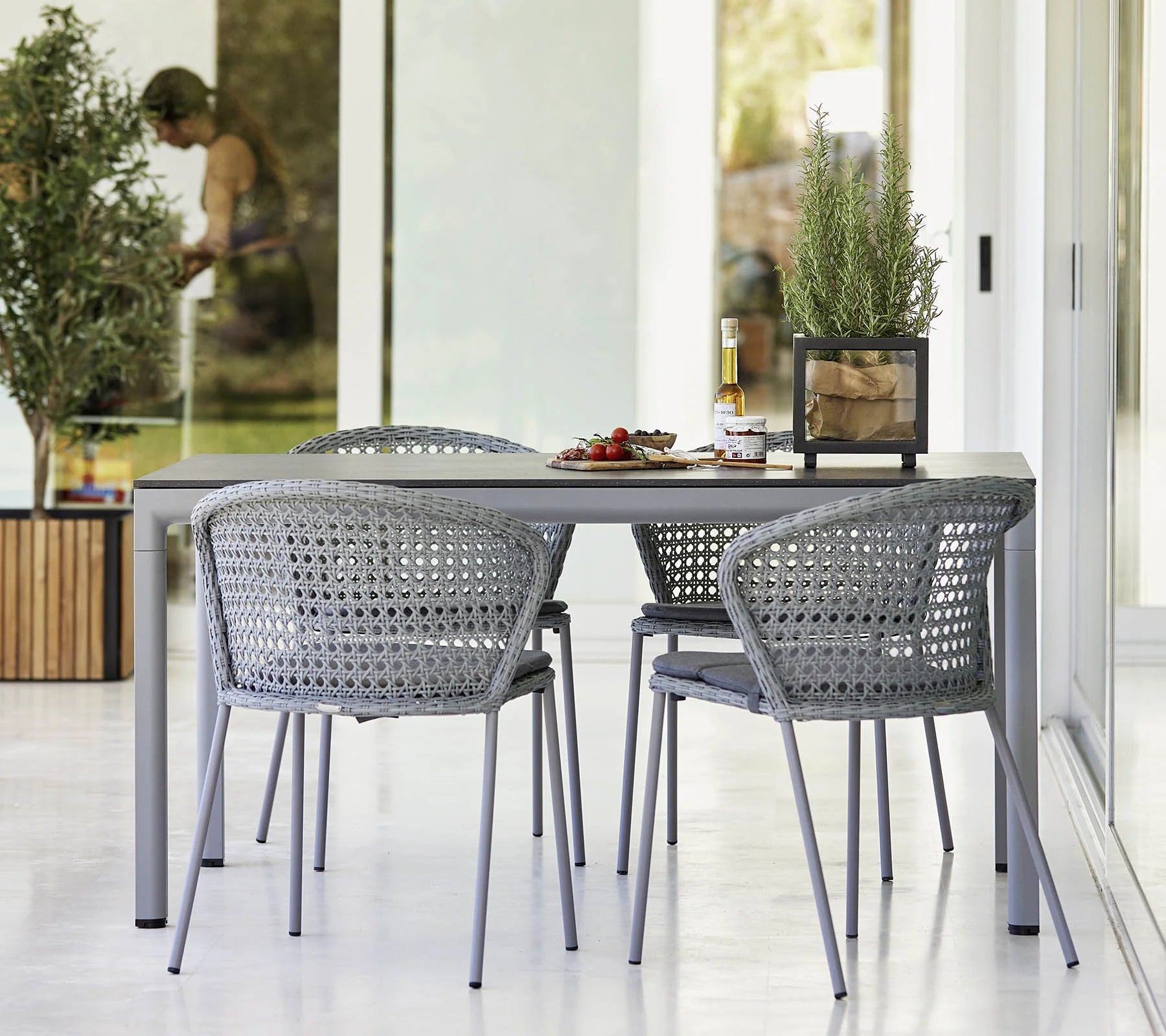 Boxhill's Lean Stackable Outdoor Garden Chair French Weave lifestyle image at patio with a dining table and random things on top