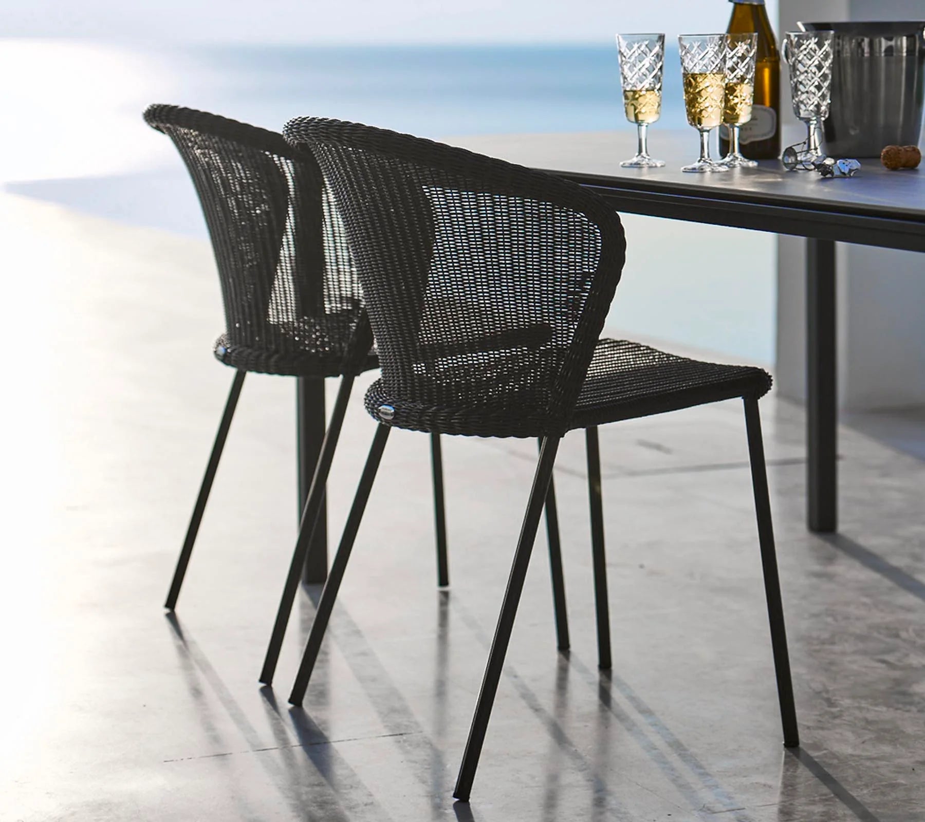 Boxhill's Lean Stackable Outdoor Garden Chair Black Weave lifestyle image with dining table with a bottle of wine, ice bucket and 4 glasses of wine on top