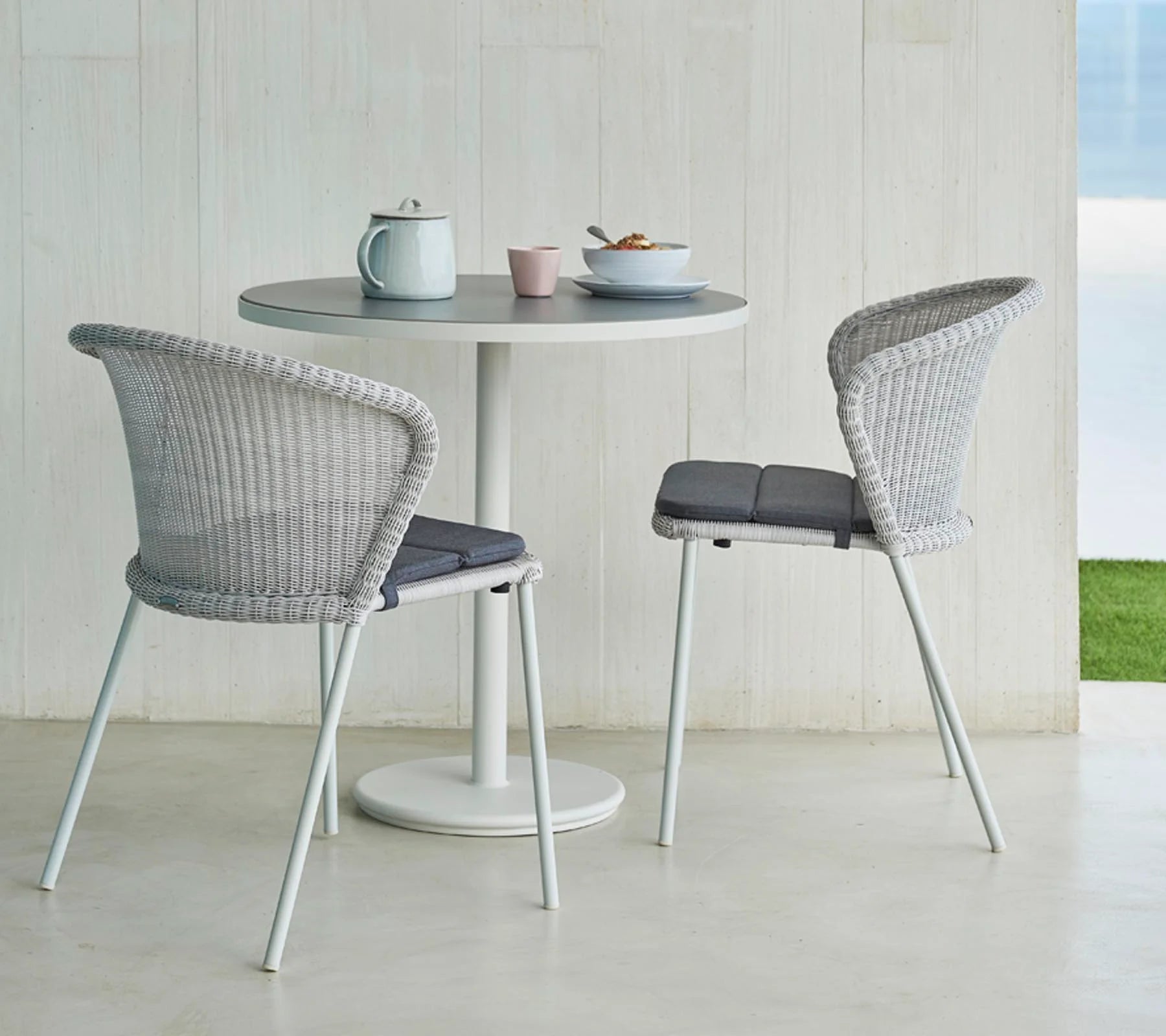 Boxhill's Lean Stackable Outdoor Garden Chair White Grey Weave lifestyle image with Round Table and a pot, cup and bowl with food on top