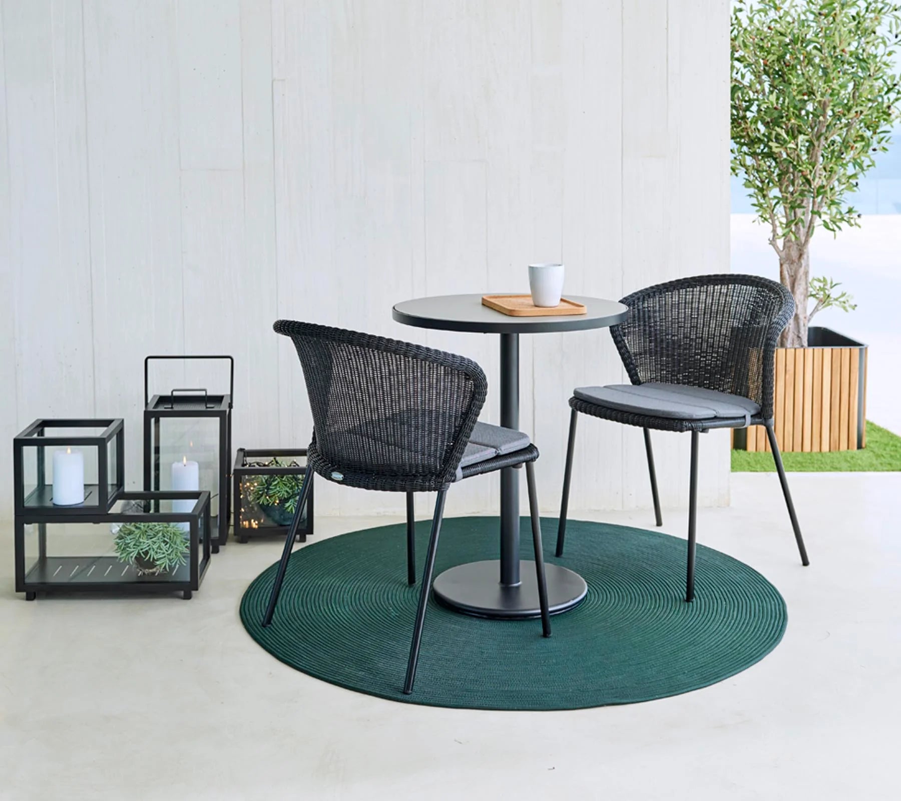 Boxhill's Lean Stackable Outdoor Garden Chair Black Weave lifestyle image with a round table and a cup on top