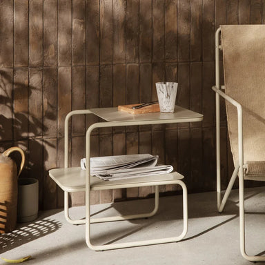 Nest of tables with a chair against a wooden wall