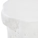 Close-up of a white textured stone or concrete stool with a smooth top surface and organic, slightly irregular edges.