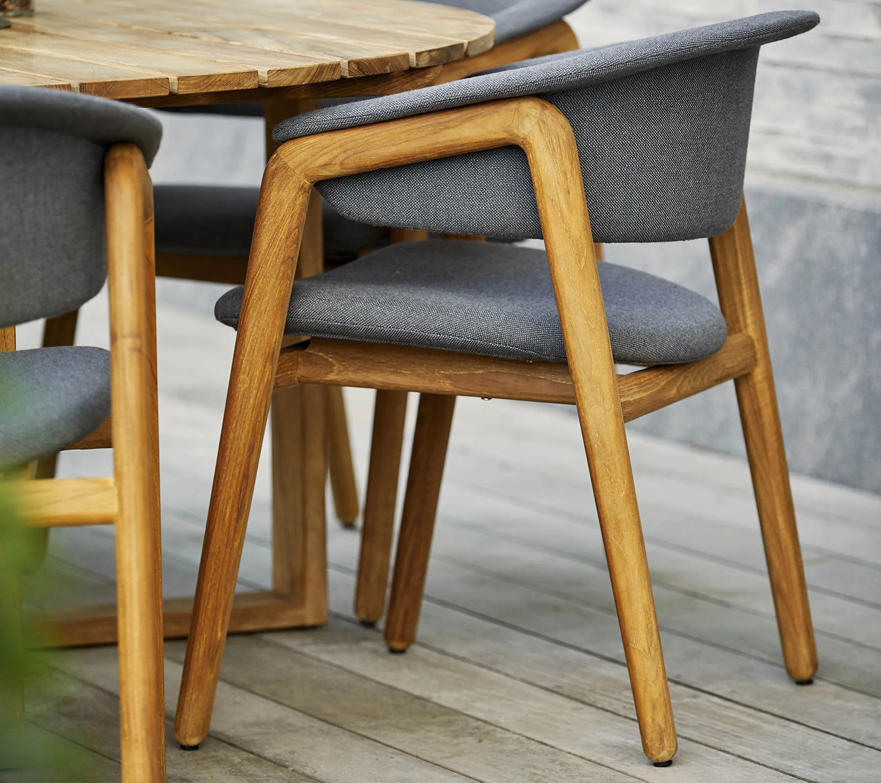 Boxhill's Luna Outdoor Dining Armchair Lifestyle image with teak round table close up view