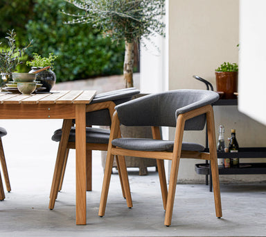 Boxhill's Luna Outdoor Dining Armchair Lifestyle image with teak dining table at patio