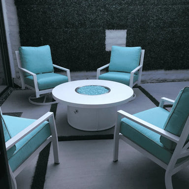 White round outdoor metal powdered coated fire pit set on a patio surrounded by four light blue cushioned chairs