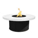 Round white tabletop with black base outdoor metal powdered coated fire pit with flames over lava rocks
