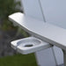 Close-up of a light gray plastic cup holder mounted on the armrest of a white Adirondack-style chair, with blurred greenery in the background.