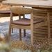 Teak outdoor armchair with brown seat cushion placed beside a wooden table