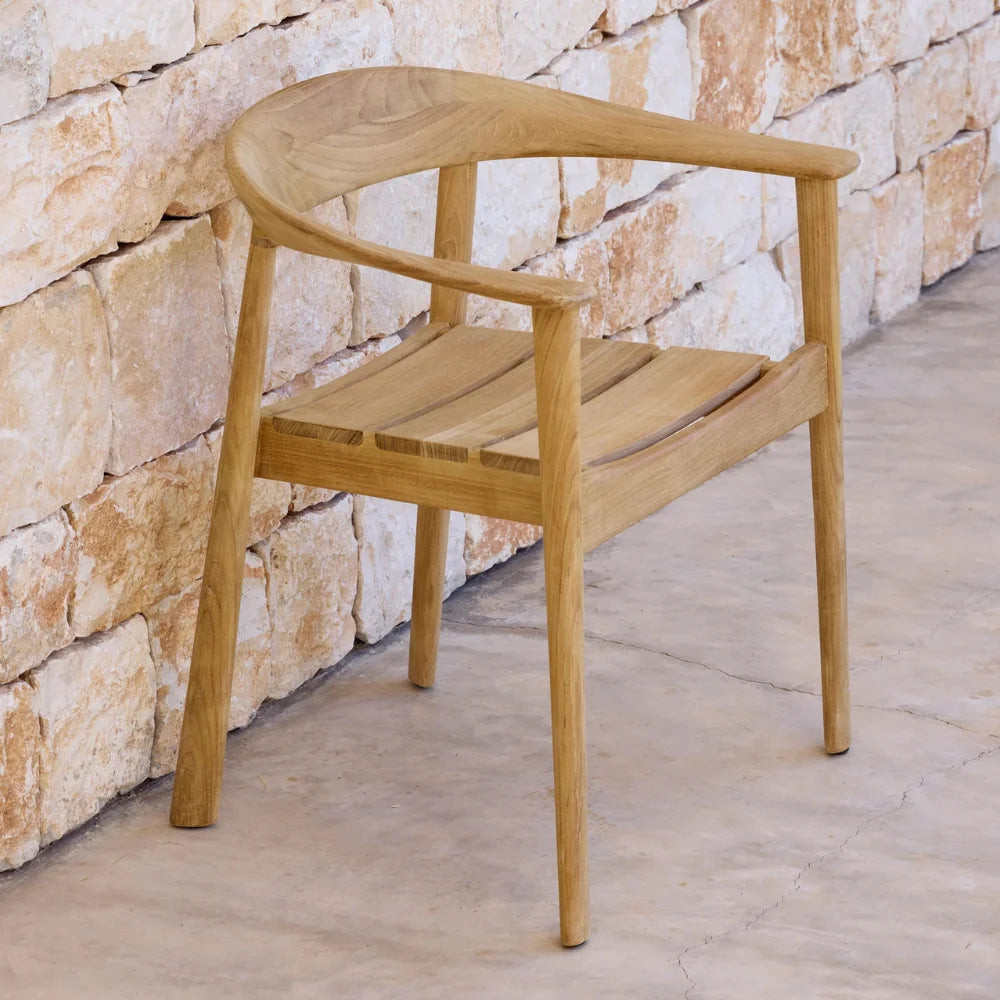 Teak outdoor armchair placed against stone wall