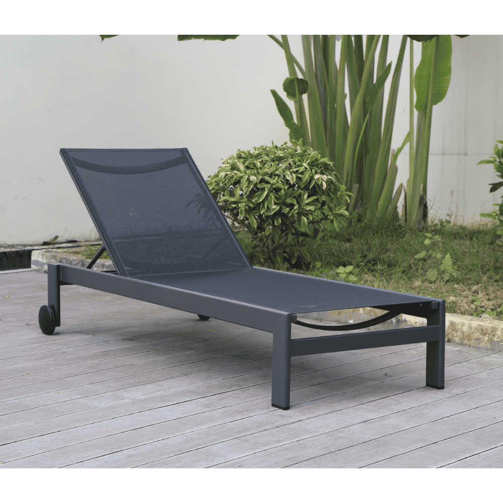Black aluminum outdoor chaise lounge with sling seat placed on a patio beside greenery