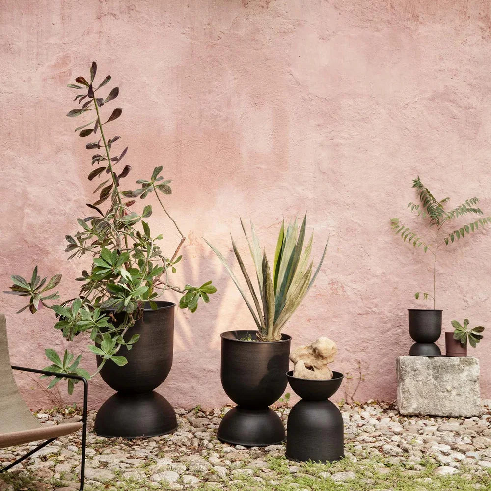 Set of black planters with plants against a pink wall