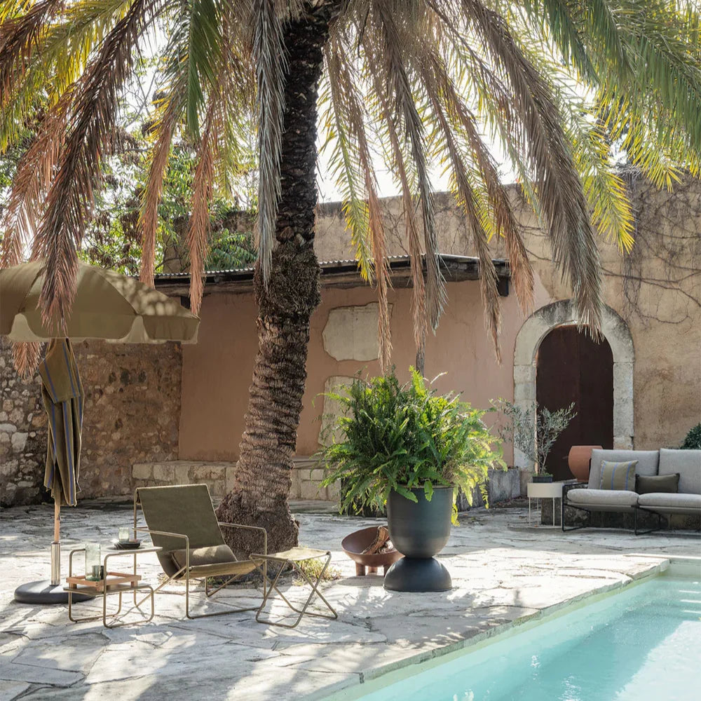 Outdoor patio area with palm tree, lounge chairs, and poolside decor.