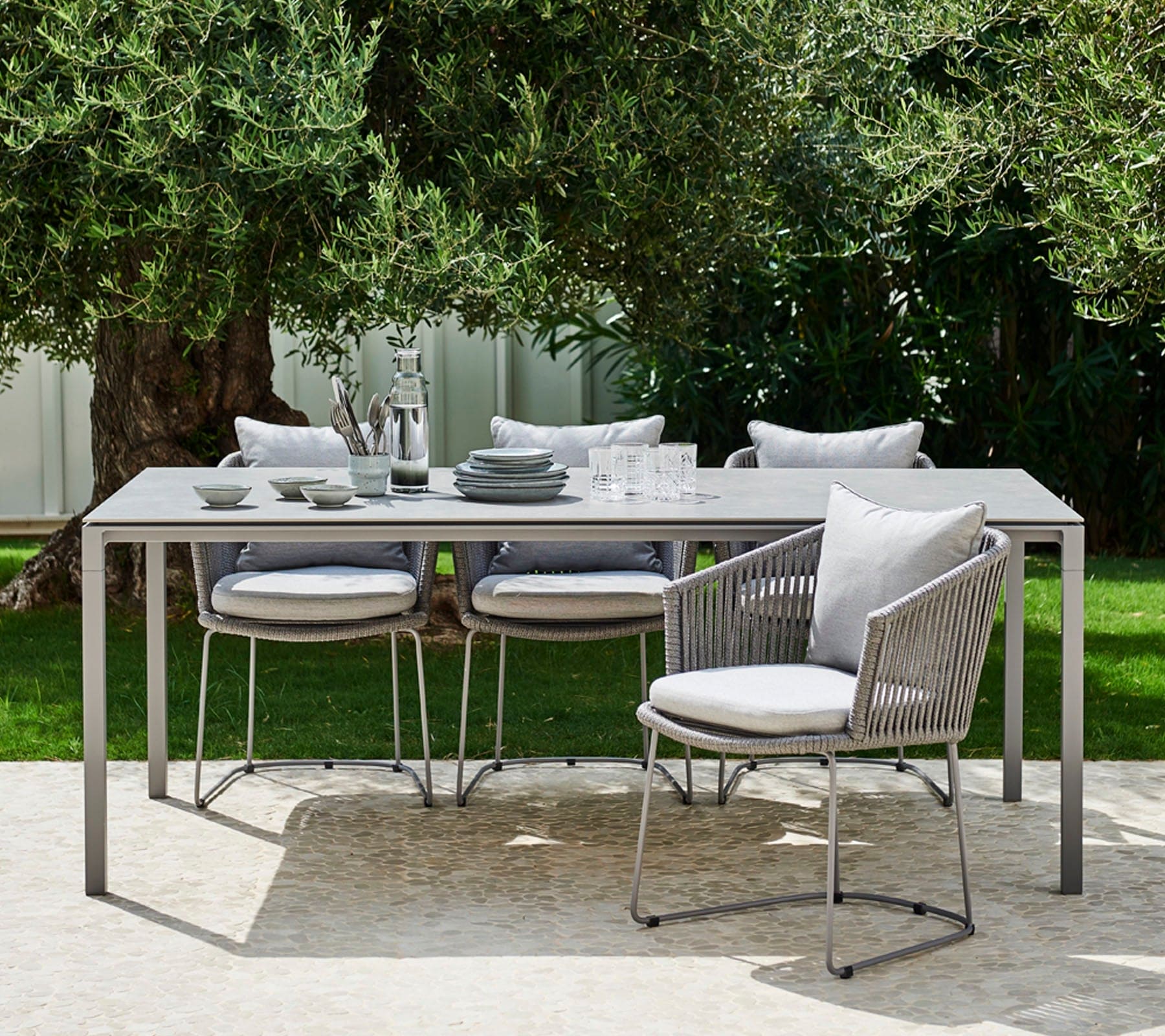Boxhill's Moments Outdoor Dining Armchair lifestyle image with dining table with random things on top at patio